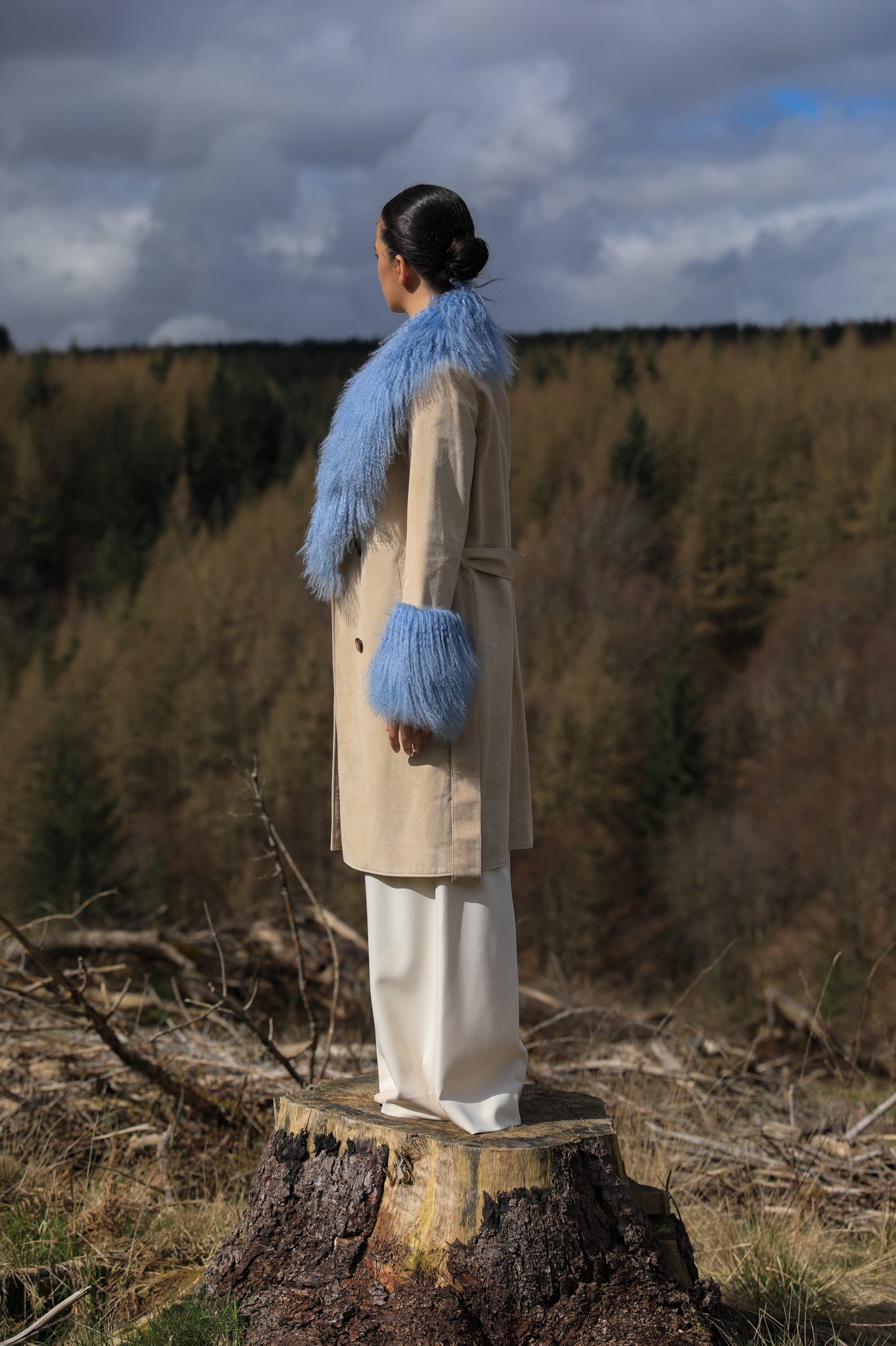 Ivory genuine suede trench wrap coat with cornflower blue Mongolian collar and cuffs by Josephine Jones. This luxurious coat exudes elegance and style, perfect for making a statement while staying warm and chic.