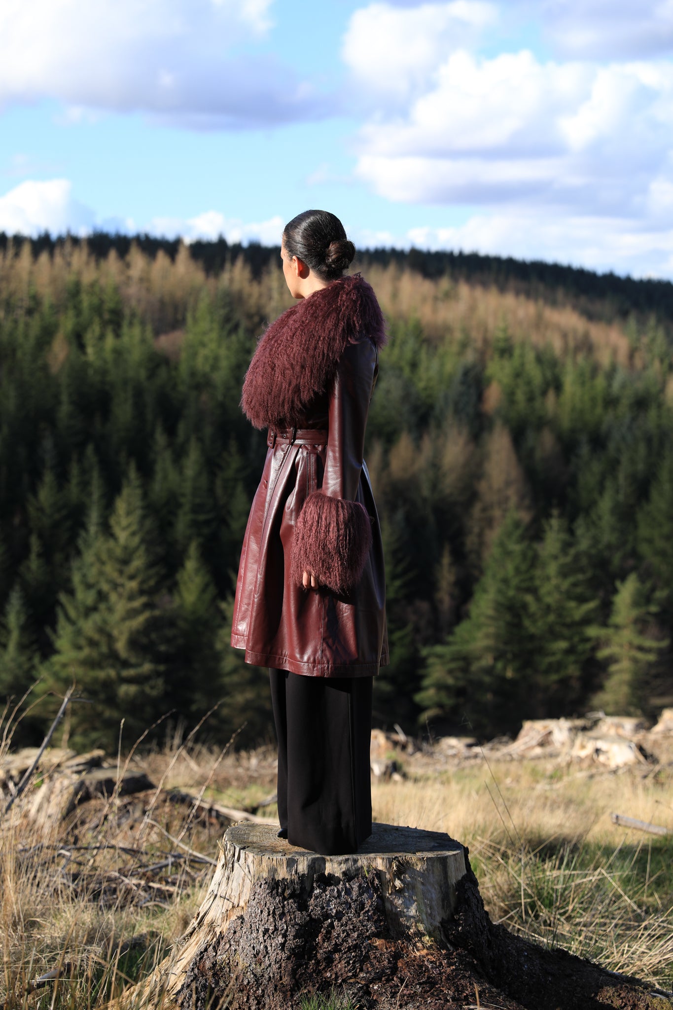 A sophisticated burgundy trench coat with a plush Mongolian collar and cuffs, crafted from genuine leather by Josephine Jones. Elevate your style with this luxurious outerwear piece.