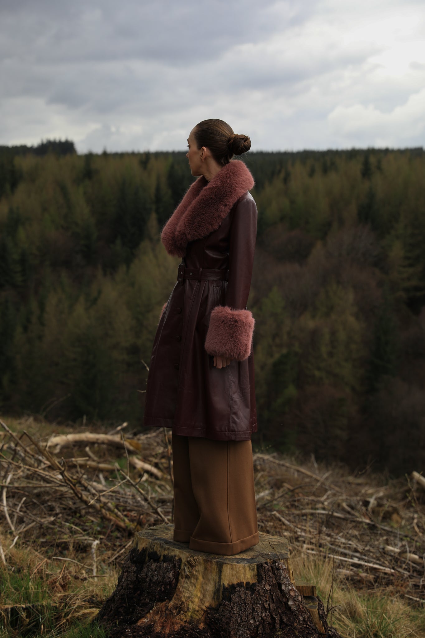 A burgundy trench coat by Josephine Jones, crafted from genuine leather, featuring a rosewood faux fur collar and cuffs. Sumptuously luxurious outerwear for the modern fashion enthusiast.