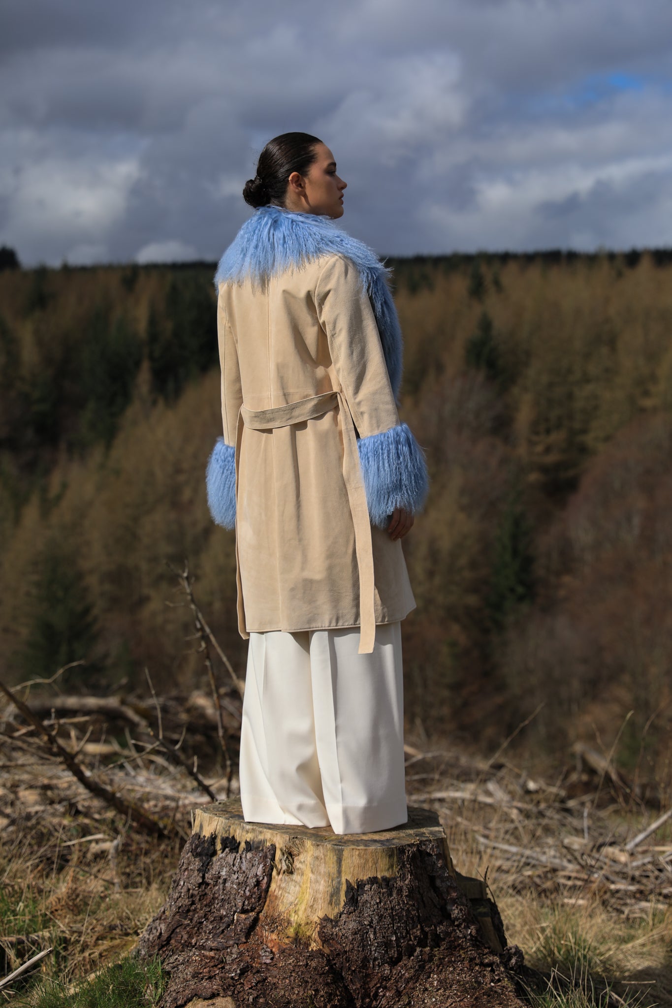 Ivory genuine suede trench wrap coat with cornflower blue Mongolian collar and cuffs by Josephine Jones. This luxurious coat exudes elegance and style, perfect for making a statement while staying warm and chic.