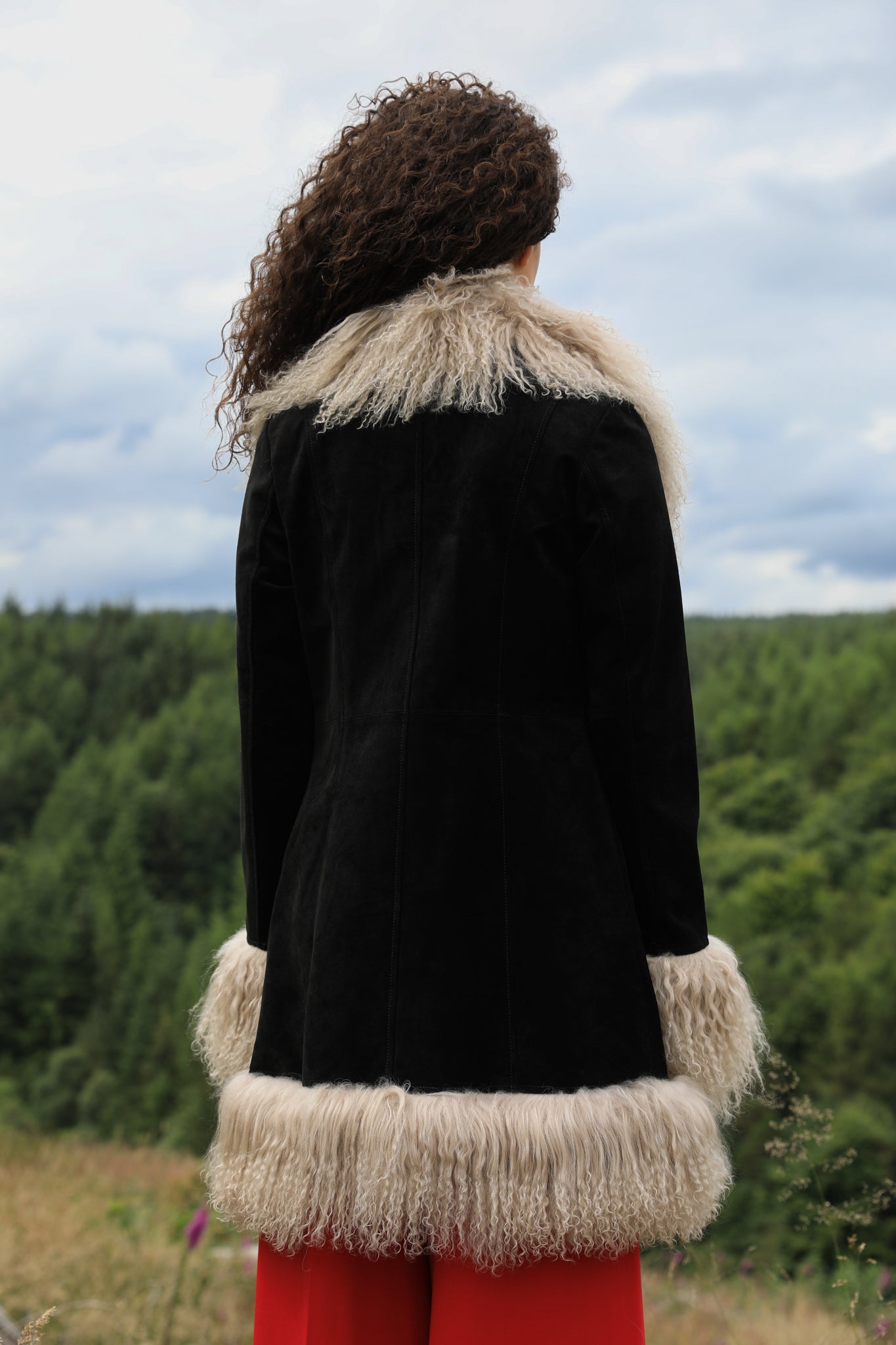 Josephine Jones' timeless black suede midi jacket with beige Mongolian fur trims, exuding classic Afghan Penny Lane style.