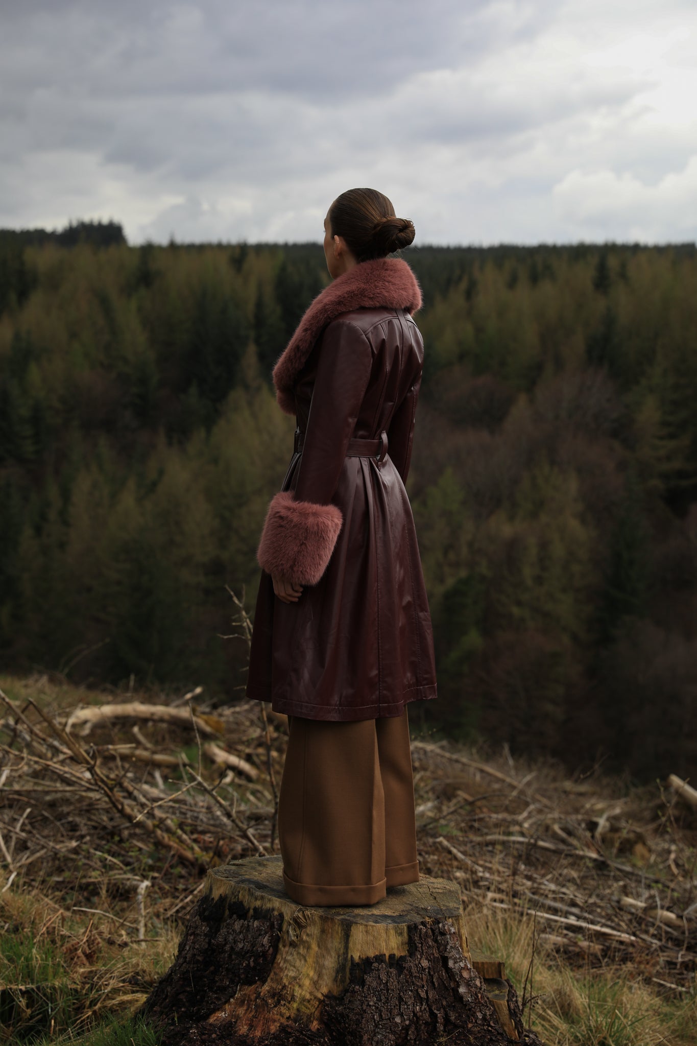 A burgundy trench coat by Josephine Jones, crafted from genuine leather, featuring a rosewood faux fur collar and cuffs. Sumptuously luxurious outerwear for the modern fashion enthusiast.