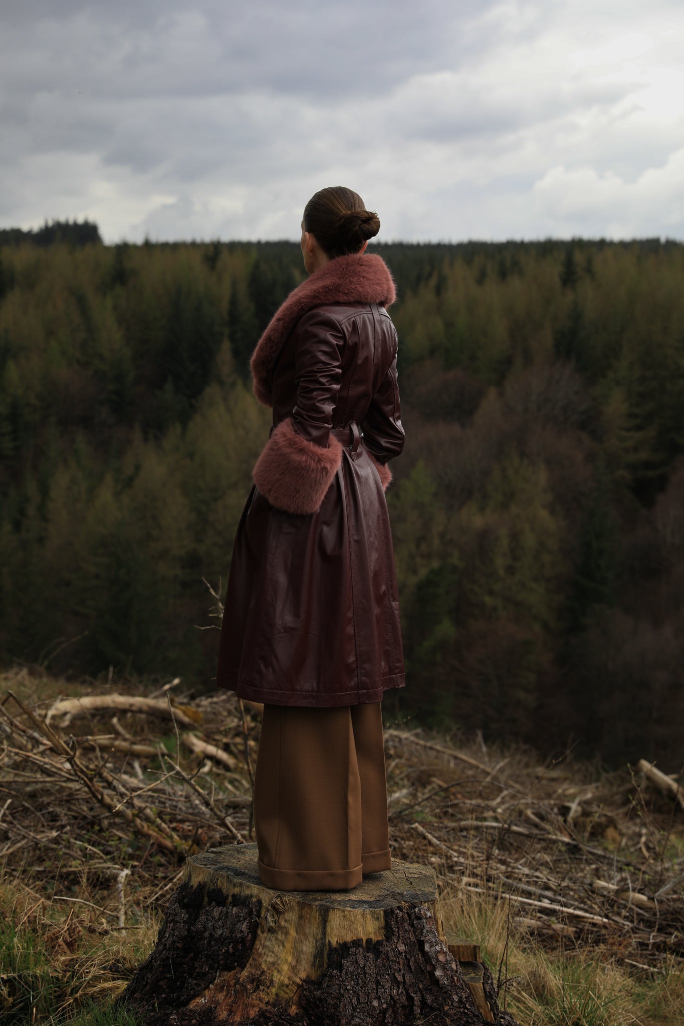 A burgundy trench coat by Josephine Jones, crafted from genuine leather, featuring a rosewood faux fur collar and cuffs. Sumptuously luxurious outerwear for the modern fashion enthusiast.