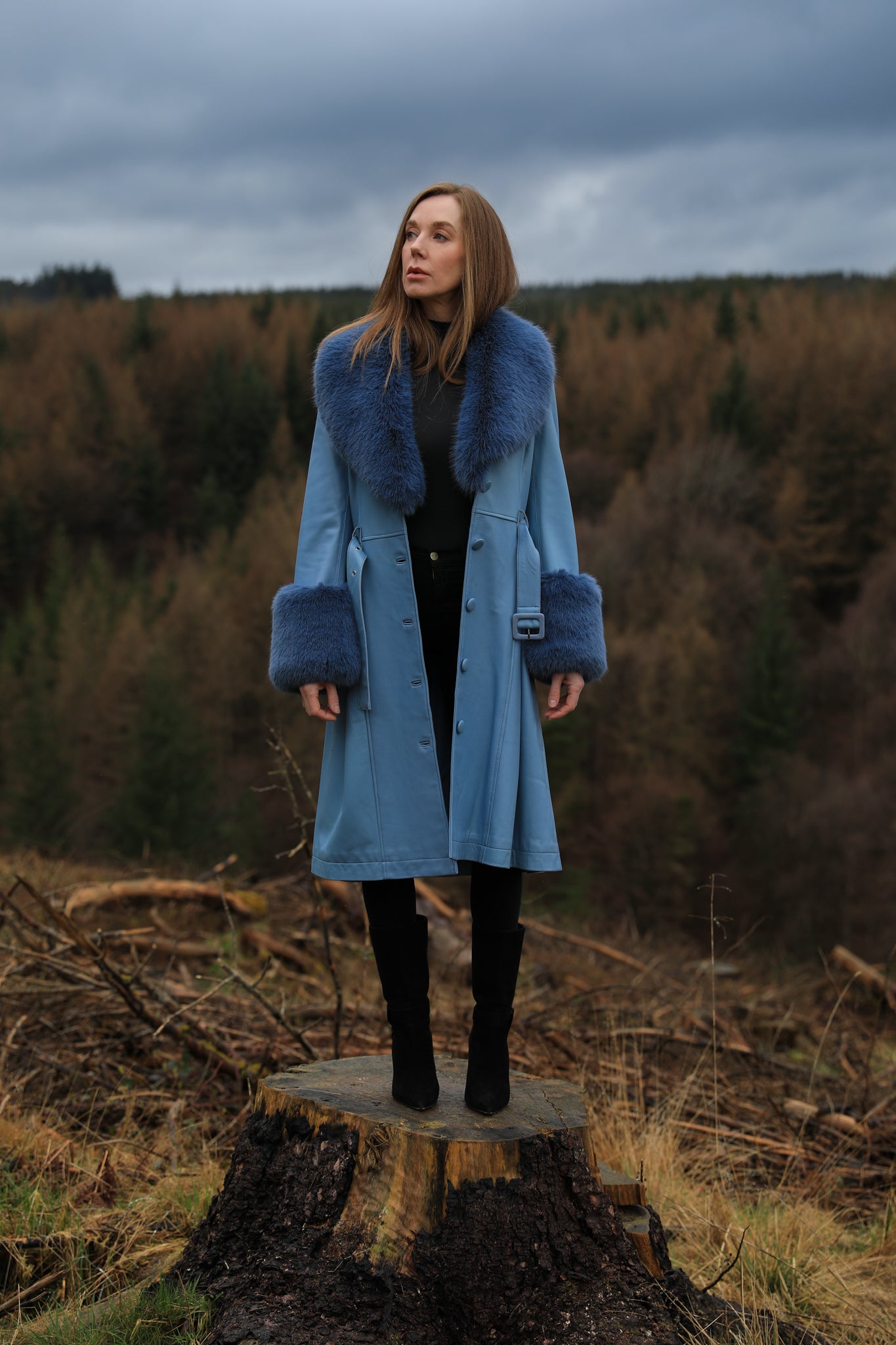  A stylish azure trench coat crafted from genuine leather, featuring a faux fur collar and cuffs, designed by Josephine Jones. Stand out in sophistication with this luxurious outerwear piece.