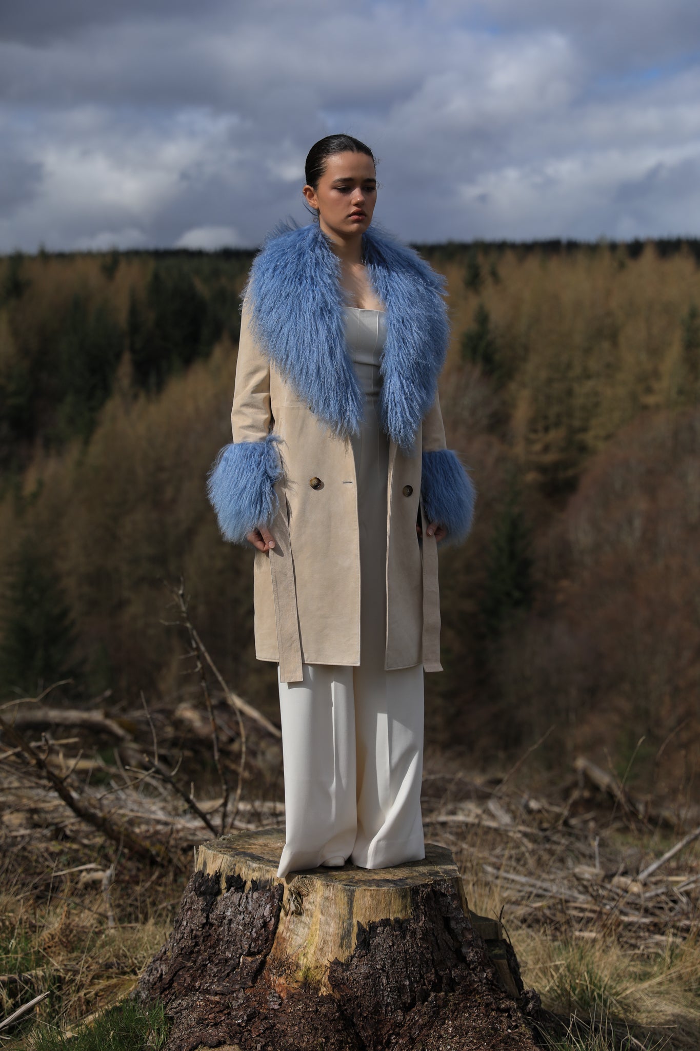 Ivory genuine suede trench wrap coat with cornflower blue Mongolian collar and cuffs by Josephine Jones. This luxurious coat exudes elegance and style, perfect for making a statement while staying warm and chic.