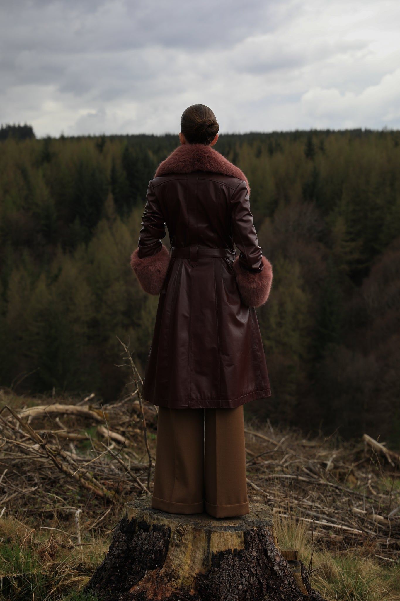 A burgundy trench coat by Josephine Jones, crafted from genuine leather, featuring a rosewood faux fur collar and cuffs. Sumptuously luxurious outerwear for the modern fashion enthusiast.