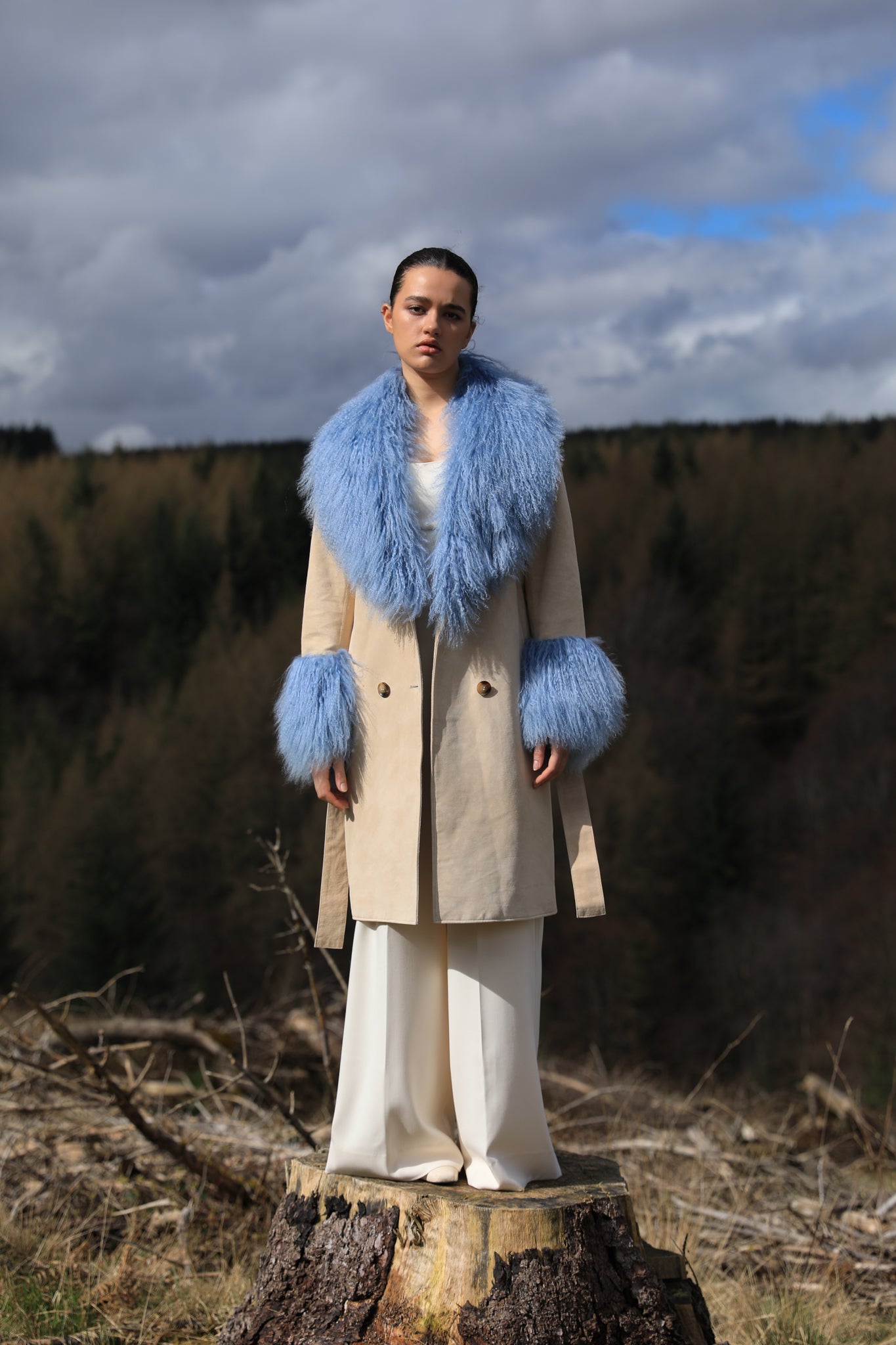 Ivory genuine suede trench wrap coat with cornflower blue Mongolian collar and cuffs by Josephine Jones. This luxurious coat exudes elegance and style, perfect for making a statement while staying warm and chic.