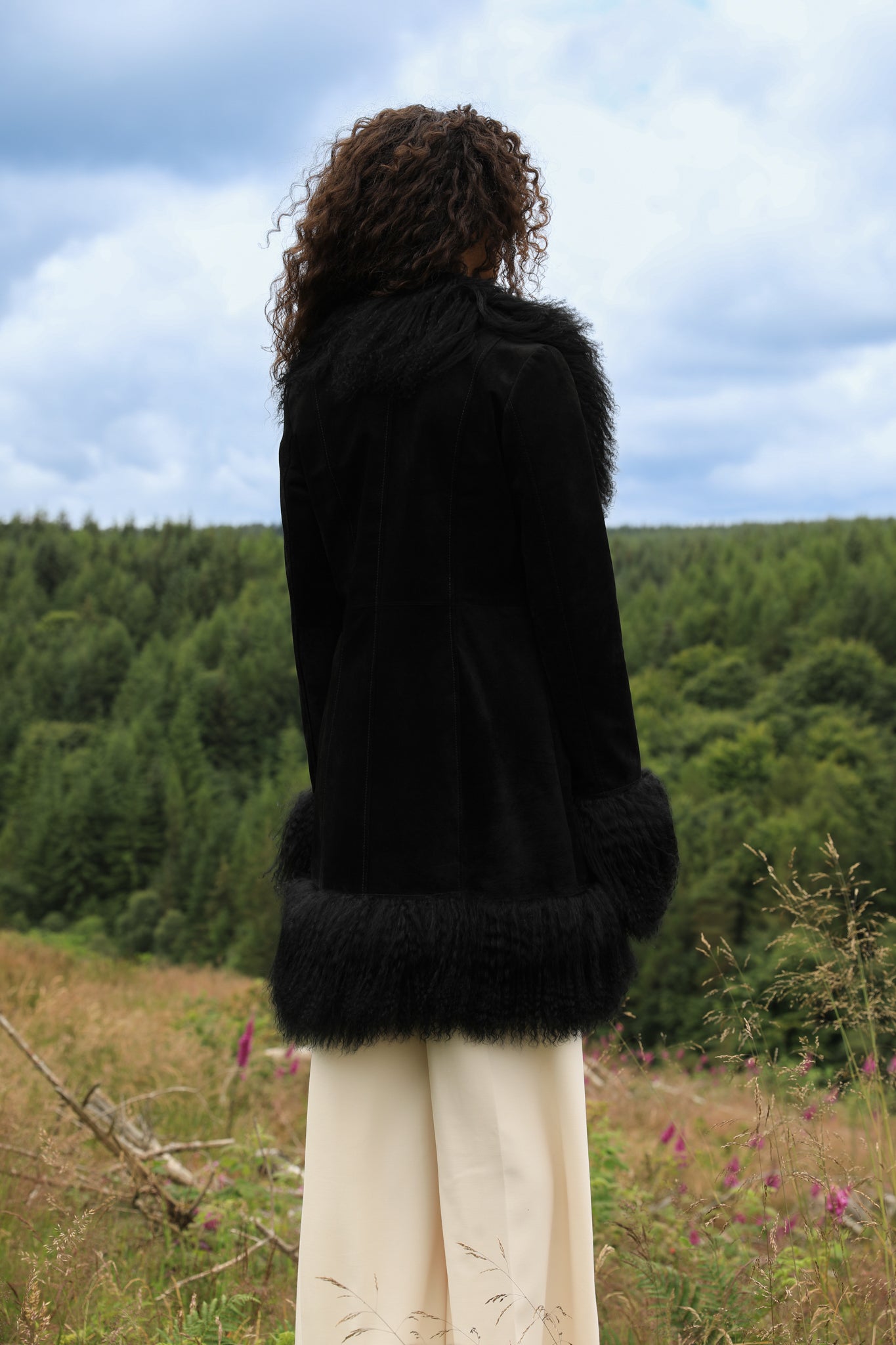 A stylish black suede midi jacket with black Mongolian fur trims, reminiscent of the iconic Penny Lane style. Crafted by Josephine Jones, this genuine suede coat exudes timeless elegance and sophistication, perfect for any fashion-forward wardrobe.