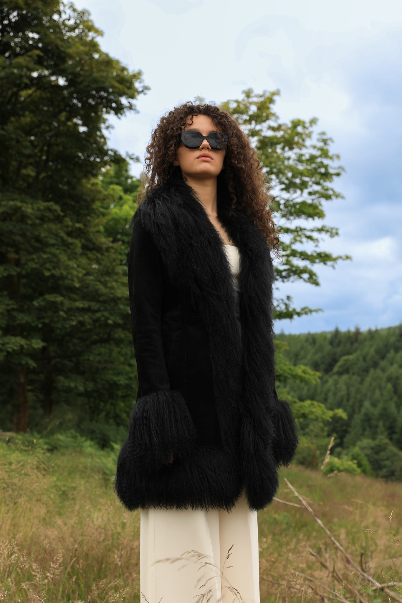 A stylish black suede midi jacket with black Mongolian fur trims, reminiscent of the iconic Penny Lane style. Crafted by Josephine Jones, this genuine suede coat exudes timeless elegance and sophistication, perfect for any fashion-forward wardrobe.