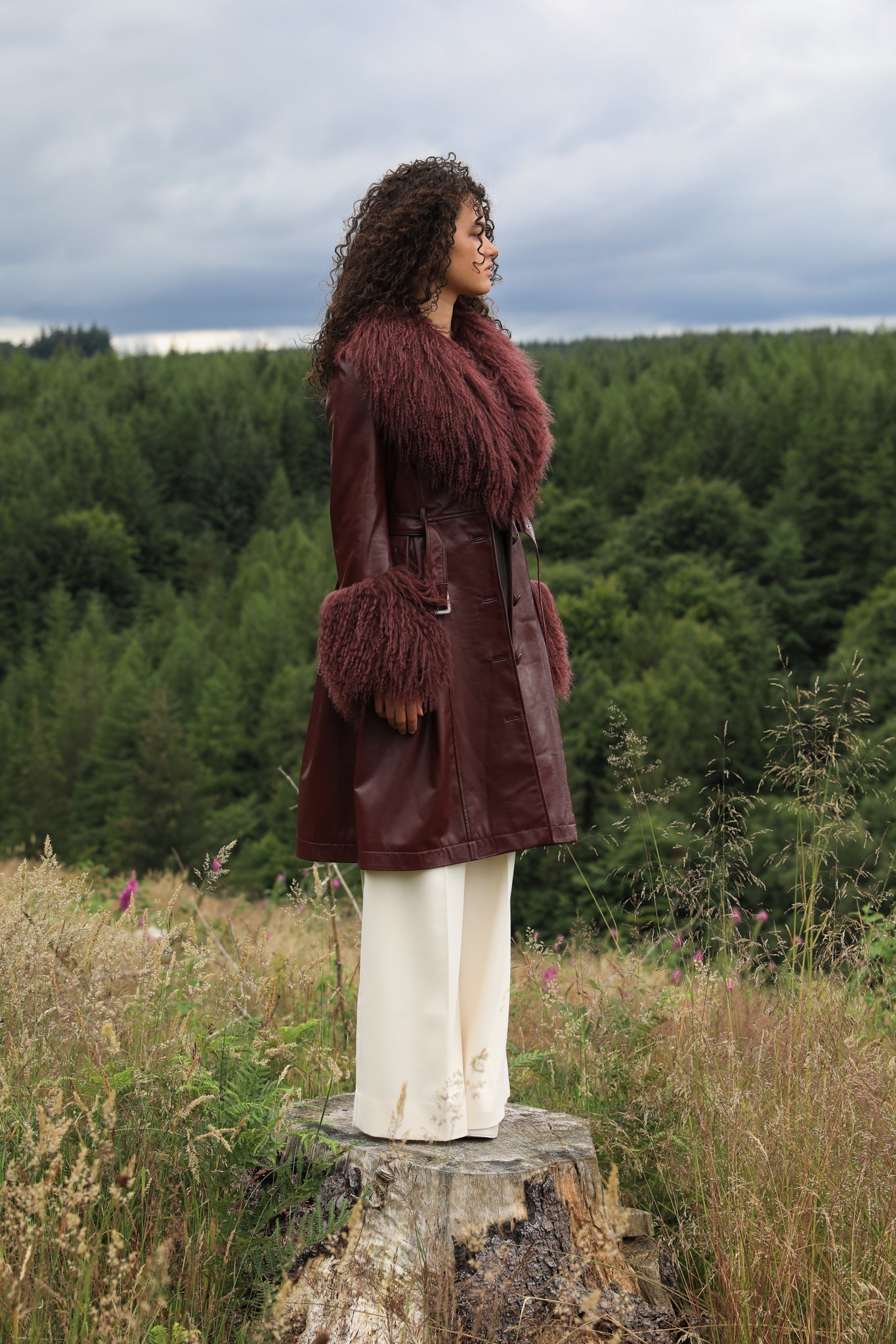 A sophisticated burgundy trench coat with a plush Mongolian collar and cuffs, crafted from genuine leather by Josephine Jones. Elevate your style with this luxurious outerwear piece.