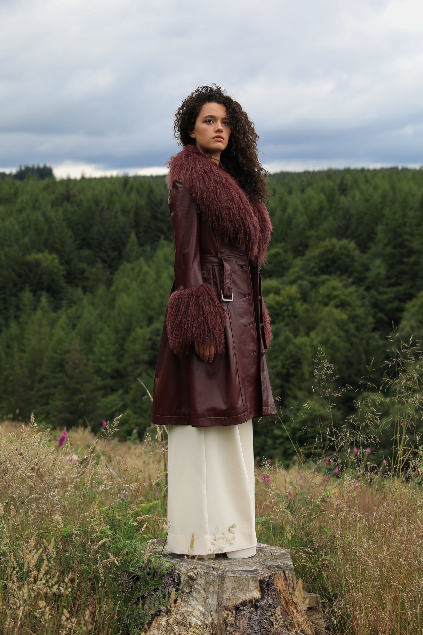 A sophisticated burgundy trench coat with a plush Mongolian collar and cuffs, crafted from genuine leather by Josephine Jones. Elevate your style with this luxurious outerwear piece.