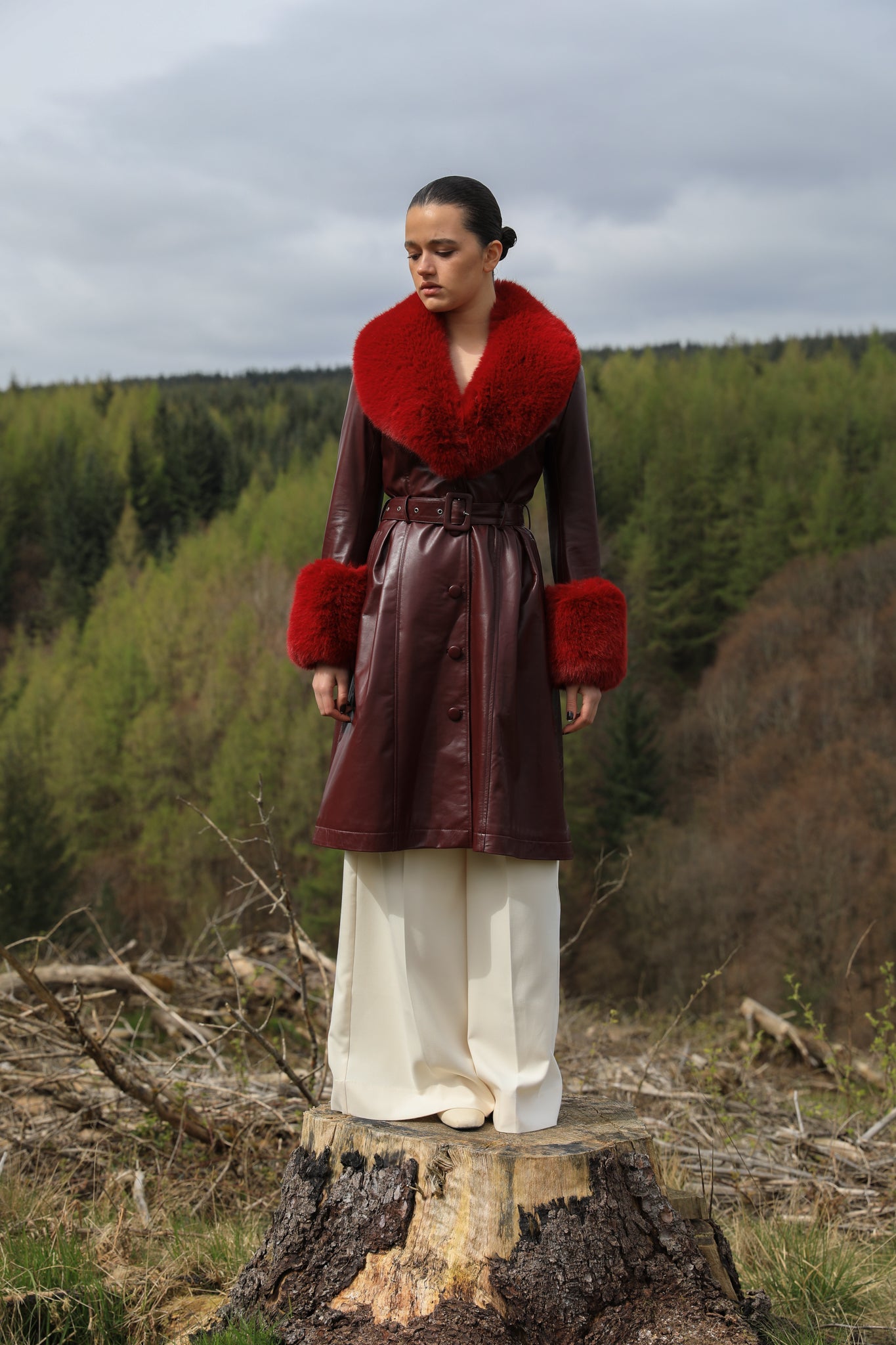 A sophisticated burgundy trench coat with Bordeaux faux fur collar and cuffs, crafted from genuine leather by Josephine Jones. This luxurious outerwear piece exudes elegance and warmth, perfect for chic winter styling.