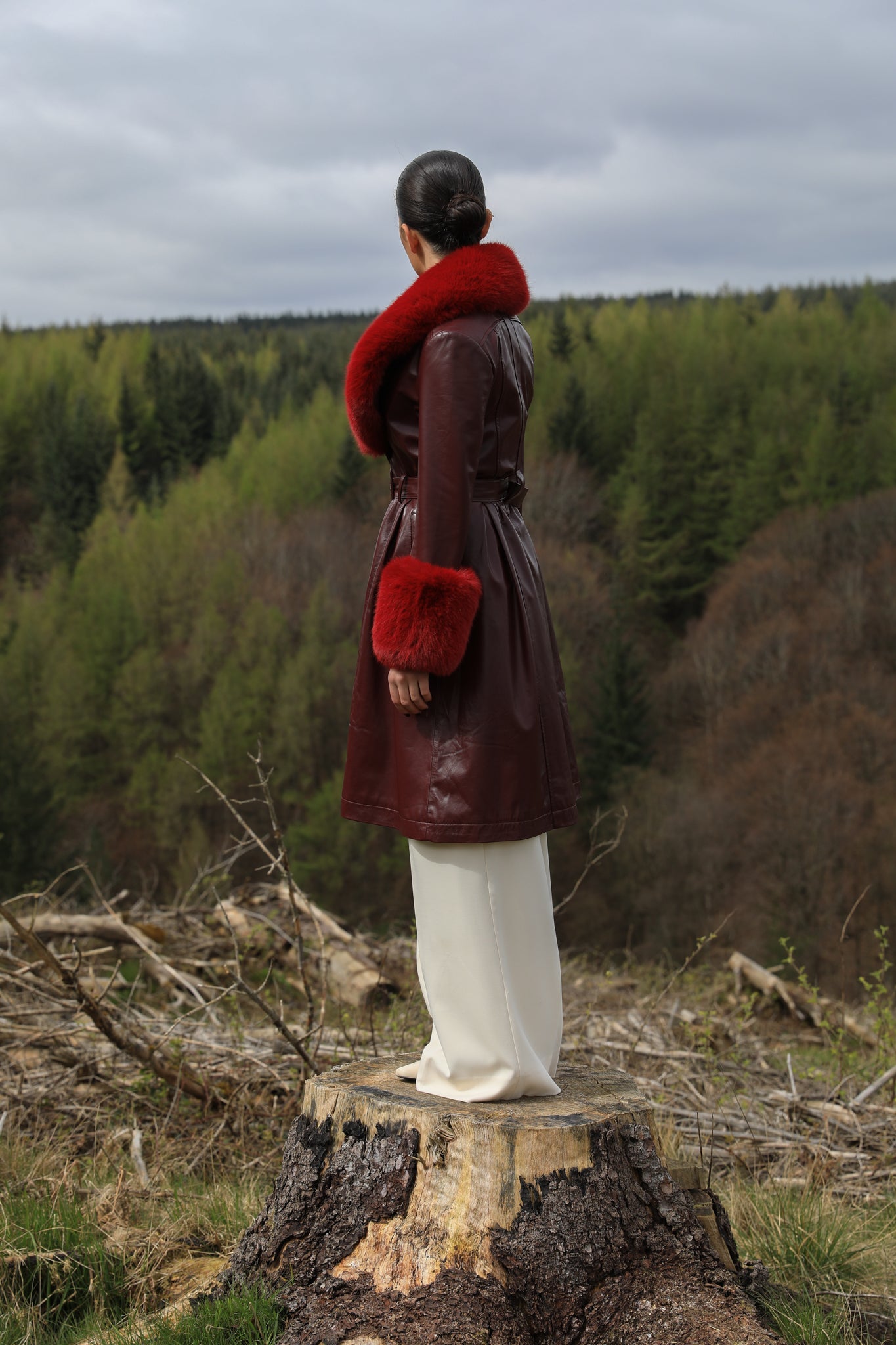 A sophisticated burgundy trench coat with Bordeaux faux fur collar and cuffs, crafted from genuine leather by Josephine Jones. This luxurious outerwear piece exudes elegance and warmth, perfect for chic winter styling.