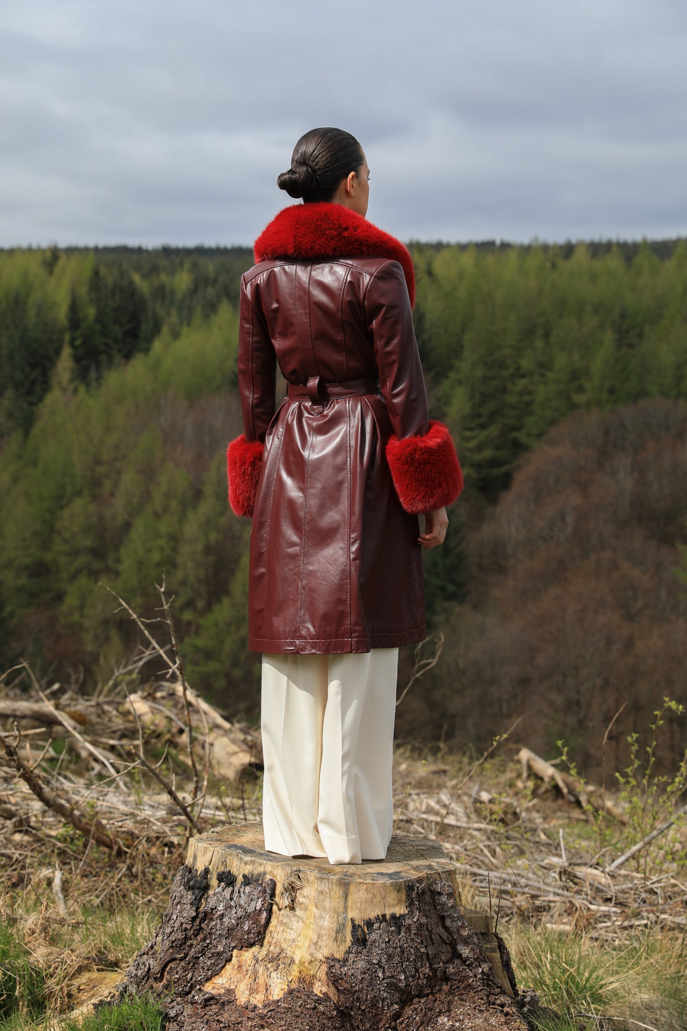 A sophisticated burgundy trench coat with Bordeaux faux fur collar and cuffs, crafted from genuine leather by Josephine Jones. This luxurious outerwear piece exudes elegance and warmth, perfect for chic winter styling.