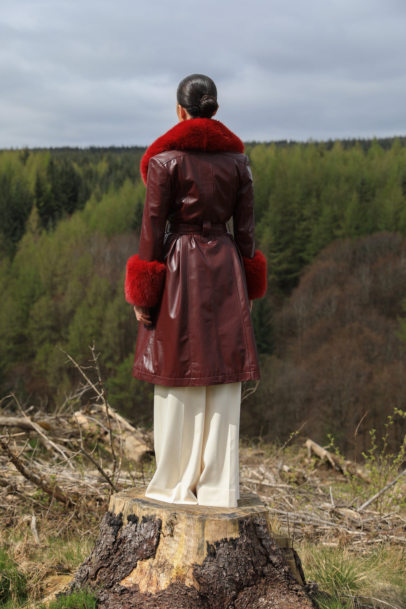 A sophisticated burgundy trench coat with Bordeaux faux fur collar and cuffs, crafted from genuine leather by Josephine Jones. This luxurious outerwear piece exudes elegance and warmth, perfect for chic winter styling.