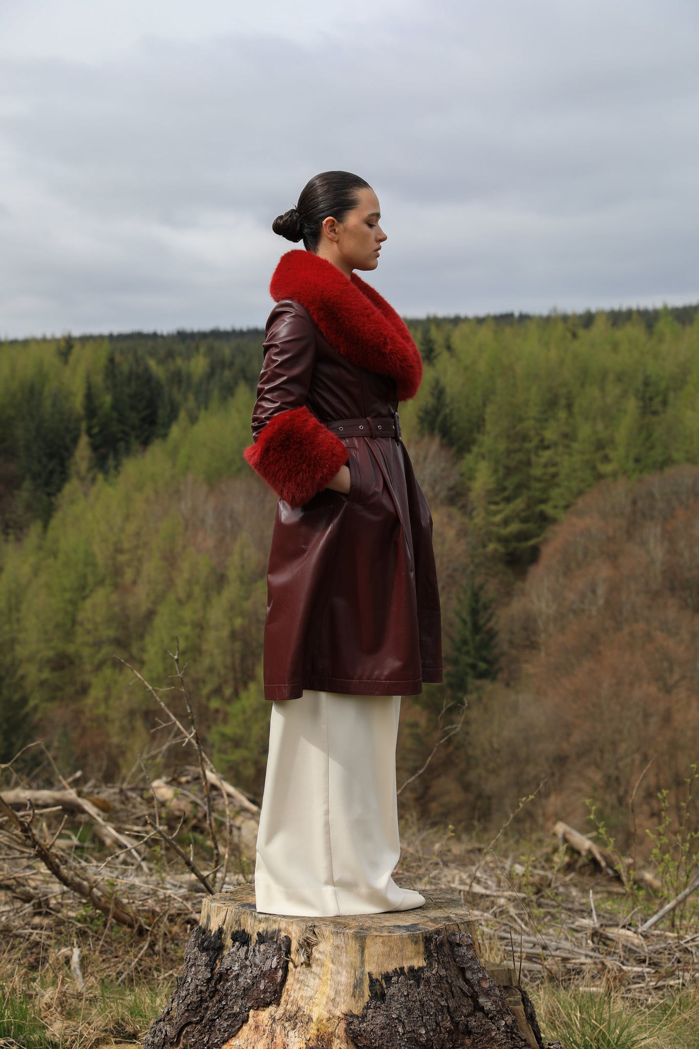 A sophisticated burgundy trench coat with Bordeaux faux fur collar and cuffs, crafted from genuine leather by Josephine Jones. This luxurious outerwear piece exudes elegance and warmth, perfect for chic winter styling.