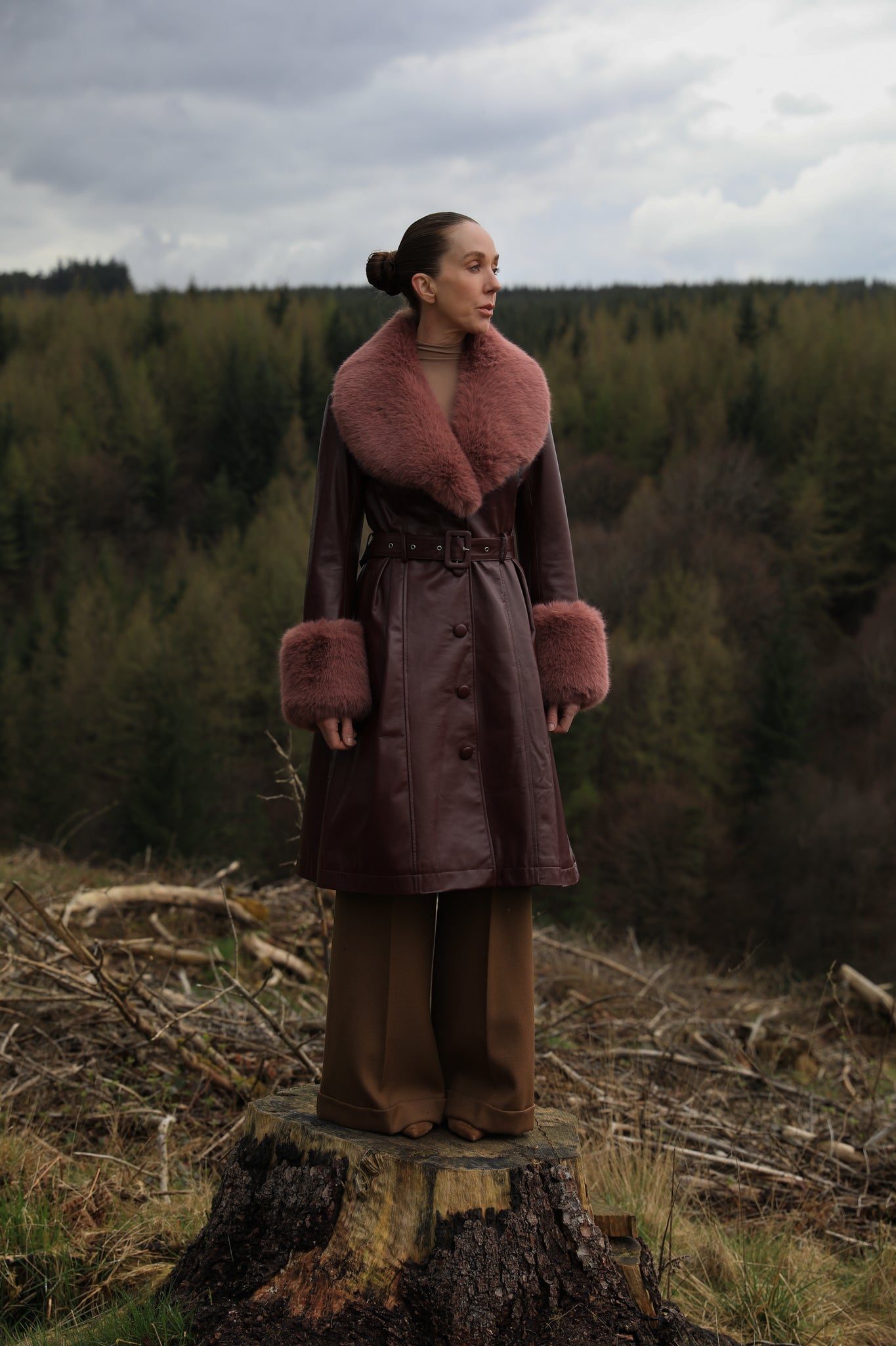 A burgundy trench coat by Josephine Jones, crafted from genuine leather, featuring a rosewood faux fur collar and cuffs. Sumptuously luxurious outerwear for the modern fashion enthusiast.