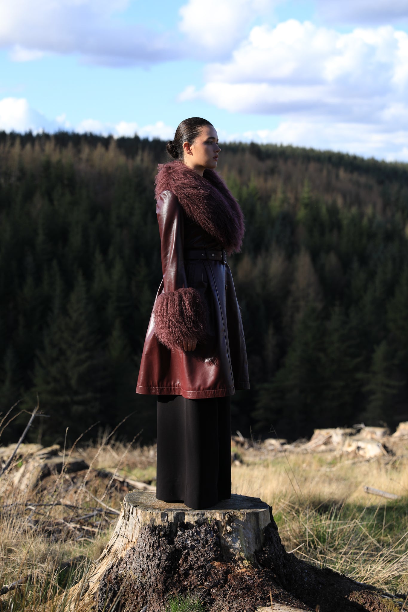 A sophisticated burgundy trench coat with a plush Mongolian collar and cuffs, crafted from genuine leather by Josephine Jones. Elevate your style with this luxurious outerwear piece.