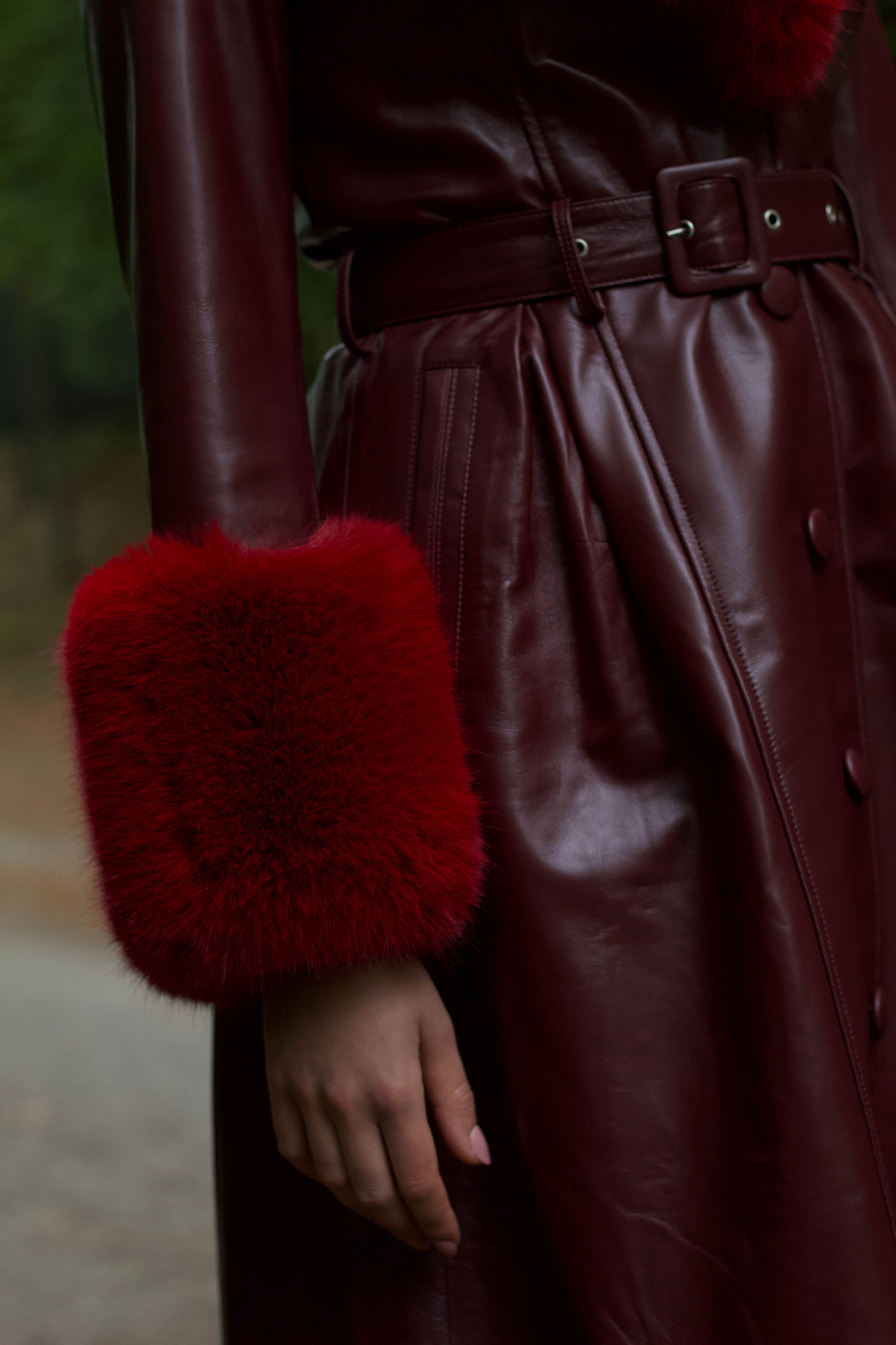 A sophisticated burgundy trench coat with Bordeaux faux fur collar and cuffs, crafted from genuine leather by Josephine Jones. This luxurious outerwear piece exudes elegance and warmth, perfect for chic winter styling.