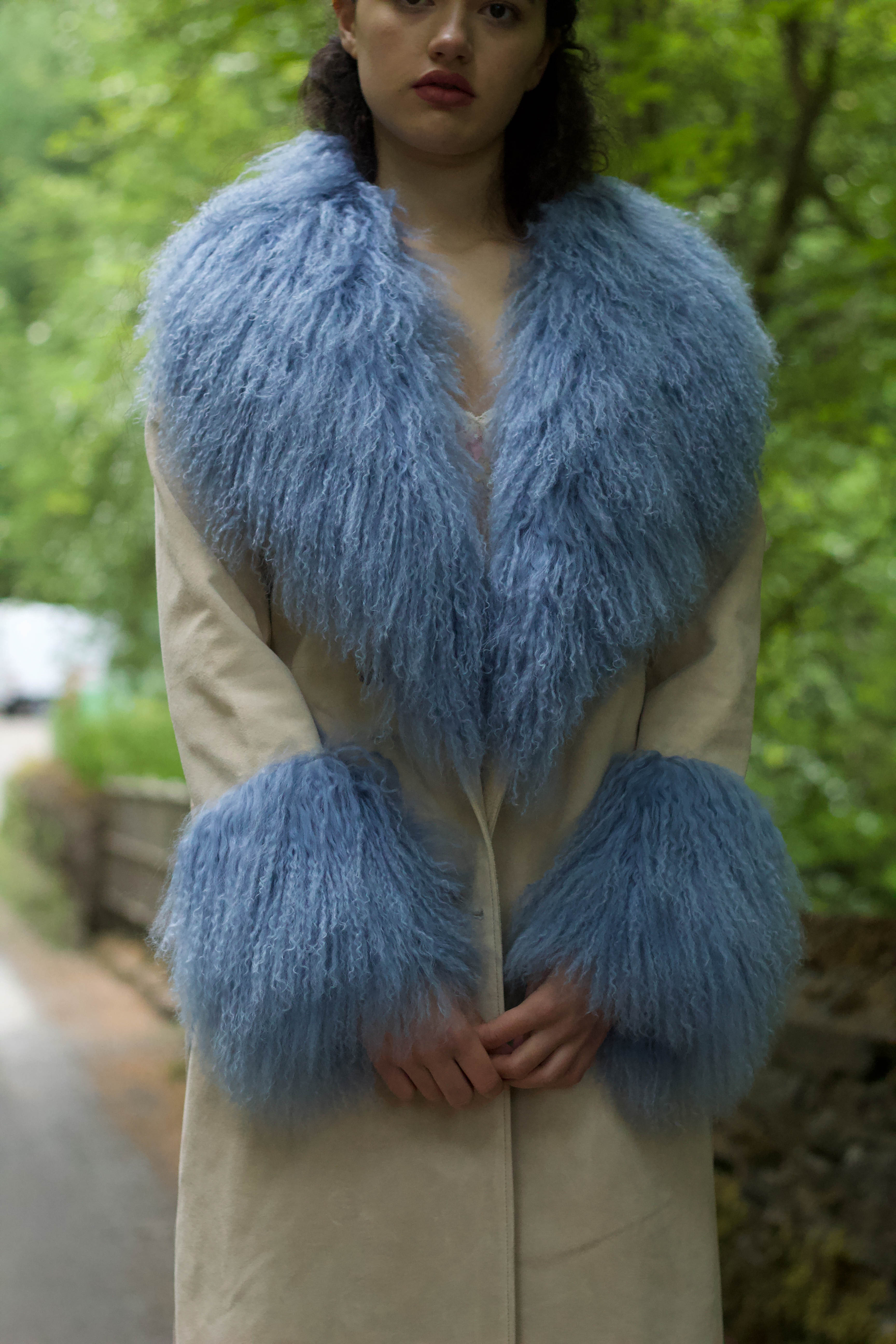 Ivory genuine suede trench wrap coat with cornflower blue Mongolian collar and cuffs by Josephine Jones. This luxurious coat exudes elegance and style, perfect for making a statement while staying warm and chic.