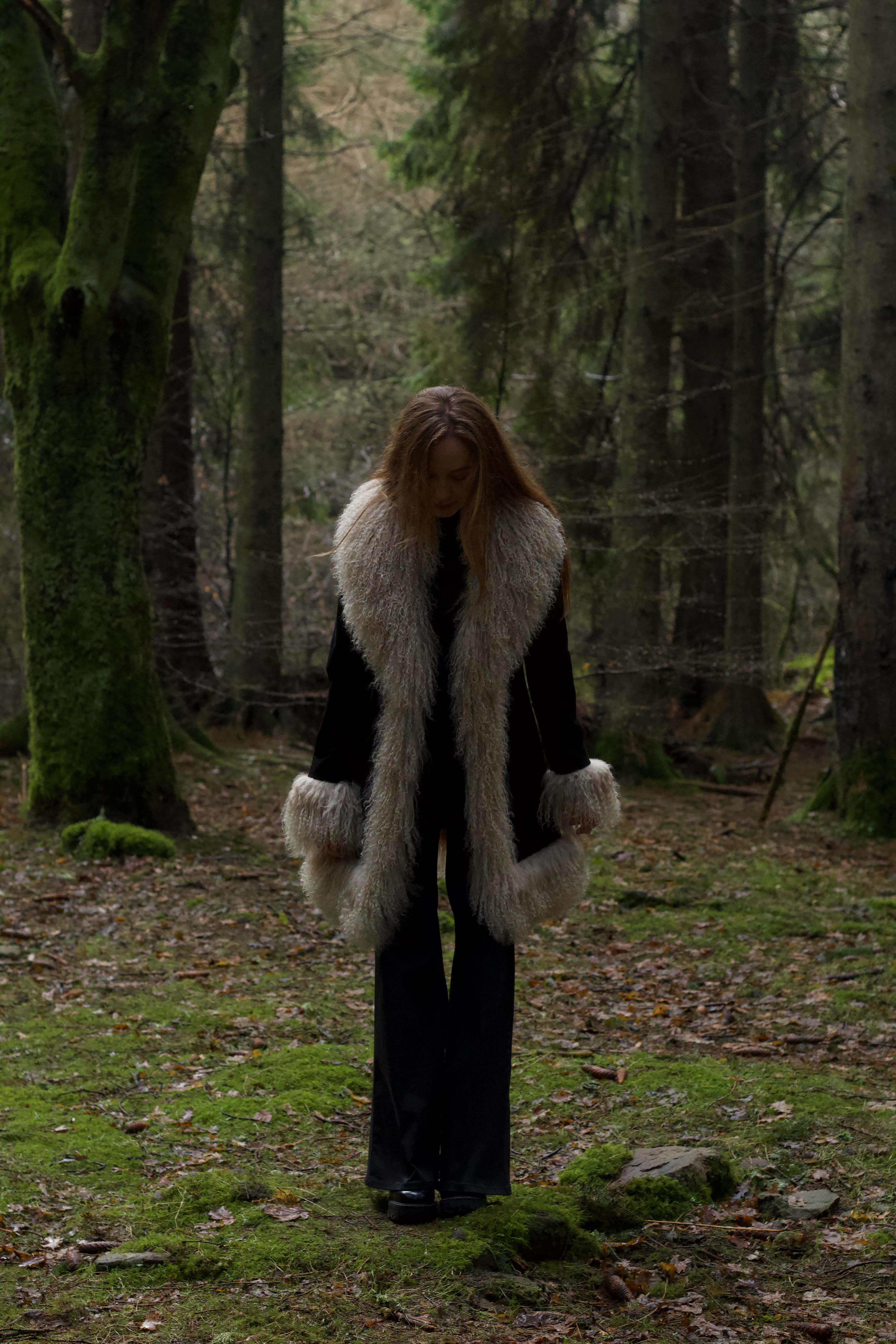 Josephine Jones' timeless black suede midi jacket with beige Mongolian fur trims, exuding classic Afghan Penny Lane style.