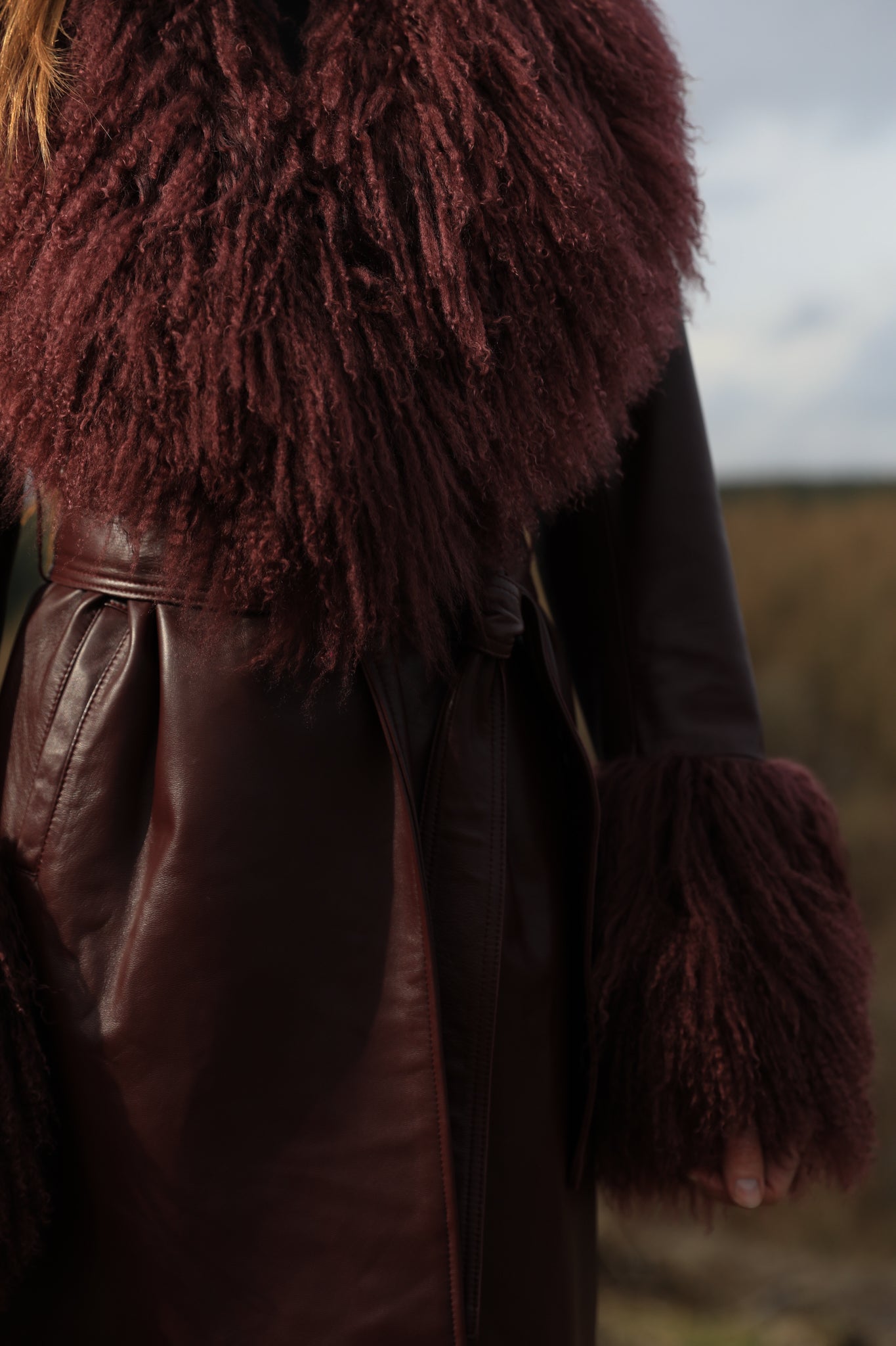 Burgundy genuine leather trench wrap coat with Mongolian collar and cuffs, designed by Josephine Jones. Luxurious outerwear exuding elegance and style