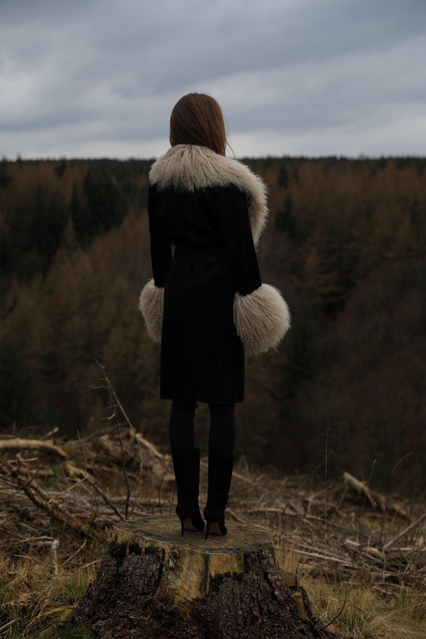 A stylish black genuine suede trench wrap coat with a beige Mongolian collar and cuffs, designed by Josephine Jones. This luxurious outerwear piece exudes sophistication and warmth, perfect for completing your winter look.